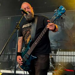 Bassist singt am Mikrofon im gelben Bühnenlicht bei Rock im Onnergrond