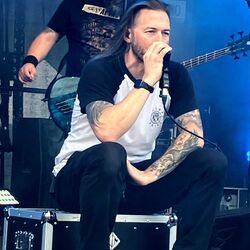 Sänger singt sitzend auf einem Flightcase im blauen Licht bei Rock im Onnergrond