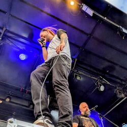 Sänger performt stehend auf einem Boxenturm mit Mikrofon bei Rock im Onnergrond