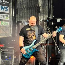 Bassist spielt energiegeladen seine blaue Bassgitarre bei Rock im Onnergrond