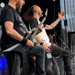 Bandmitglieder stehen zusammen und musizieren auf der Bühne bei Rock im Onnergrond