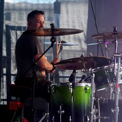 Schlagzeuger von Miles2Fall spielt lachend am gruenen Schlagzeug beim Festival Rock im Onnergrond