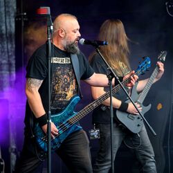 Bassist von Miles2Fall singt ins Mikrofon vor violettem Buehnenlicht beim Festival Rock im Onnergrond