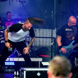 Sänger mit fliegenden Haaren bewegt sich energiegeladen auf der Bühne bei Rock im Onnergrond