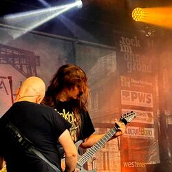 Zwei Gitarristen spielen zusammen im dramatischen Scheinwerferlicht bei Rock im Onnergrond