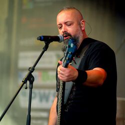 Bassist mit Bart singt leidenschaftlich ins Mikrofon bei Rock im Onnergrond