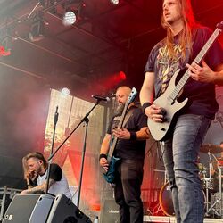 Band performt gemeinsam im intensiven roten Bühnenlicht bei Rock im Onnergrond
