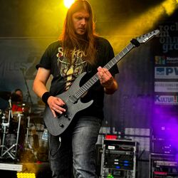 Langhaariger Gitarrist spielt im gelben Scheinwerferlicht bei Rock im Onnergrond
